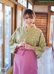 A woman in a green and pink kimono posing for a picture.