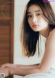 A woman with long brown hair sitting on a bed.